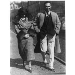 Edsel Bryant Ford,with wife,walking toward camera on sidewalk,smiling 