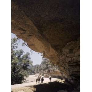  Horseback Riders Stand Near a Caves Large Opening 